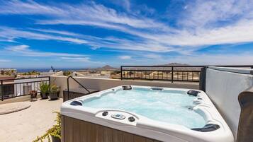 A hot tub on a rooftop with a clear view of the city skyline and mountains in the distance.