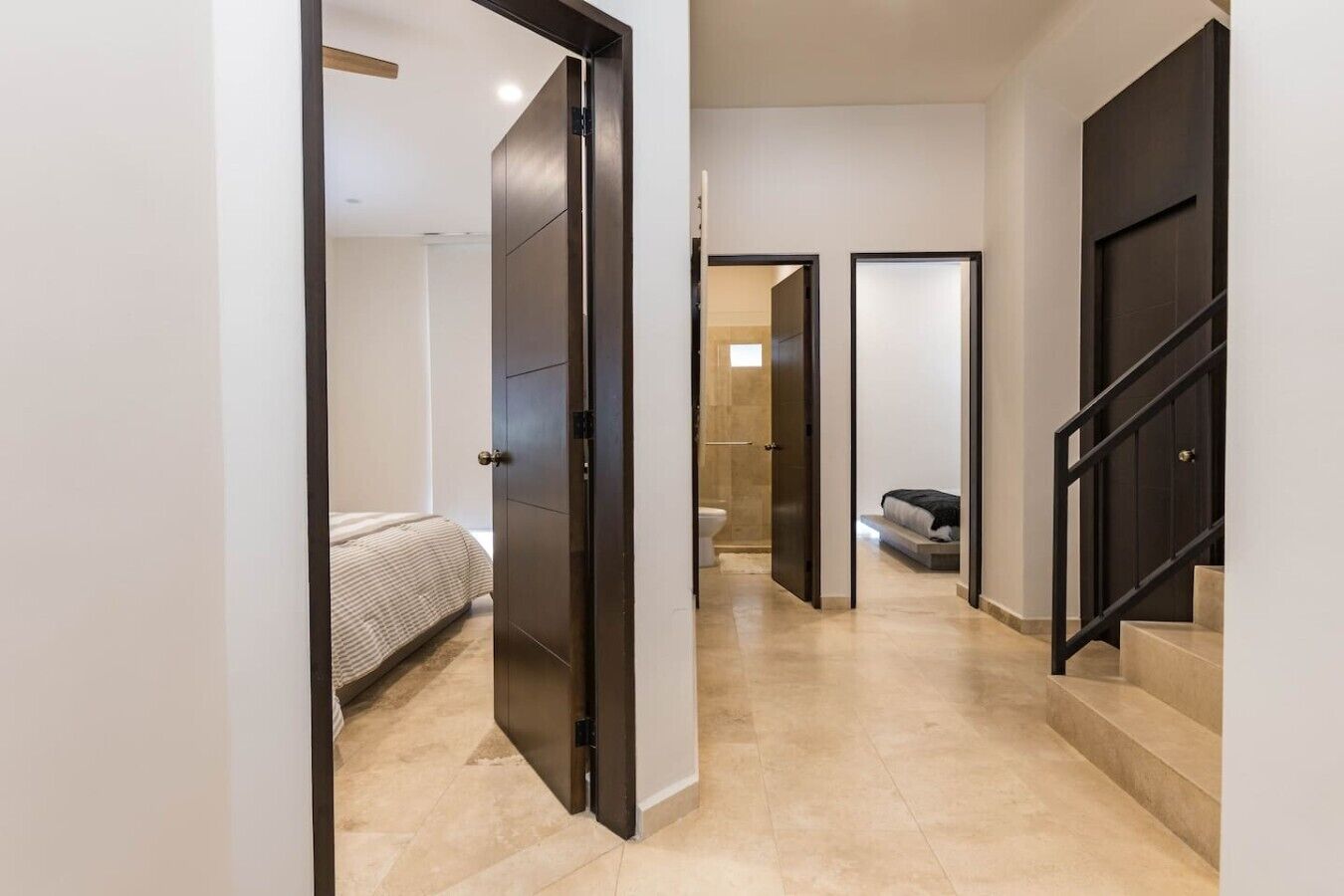 A hallway with a bed, a bathroom, and a staircase.