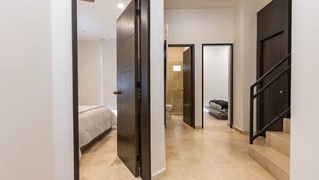 A hallway with a bed, a bathroom, and a staircase.
