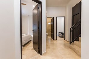 Un pasillo con una cama, un baño y una escalera.