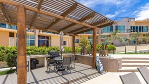 An outdoor patio area with a grill, seating, and a covered structure.