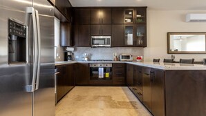 A modern kitchen with stainless steel appliances, dark cabinetry, and a granite countertop.