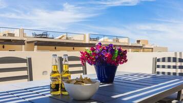 A table with two bottles of Corona Extra beer, a bowl of chips, and a potted plant with purple flowers.