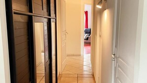 A hallway with a tiled floor, a door with a black frame, and a red curtain in the background.