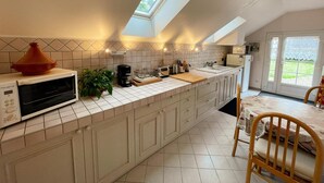 A modern kitchen with a skylight, white cabinets, a built-in oven, and a dining area with a table and chairs.
