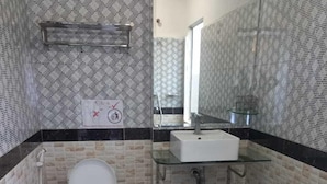 A bathroom with a toilet, a glass sink, and a shower. - Hotel Selver Shinn & Restaurant (Phnom Penh)