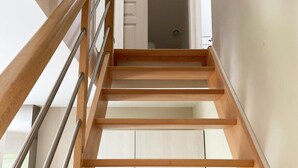 Un escalier en bois avec des rampes en métal menant à une porte blanche.