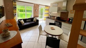 Un salon moderne comprenant un canapé, une table à manger et un coin cuisine avec des placards et des appareils électroménagers.