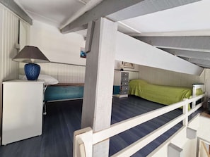 A compact room with bunk beds, a desk with a lamp, and a dresser.