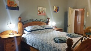 A bedroom with a wooden bed, two bedside tables with lamps, a wooden dresser, and a door. - Historic Tyford House, close to all amenities (Dongara)