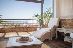 A balcony with wicker furniture, a stone wall, and a view of the city. - Quiet apartment with views, terrace and close to beach and downtown (Málaga)