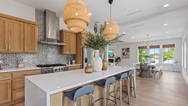 A modern kitchen with wooden cabinets, a white marble countertop, and a central island with bar stools.