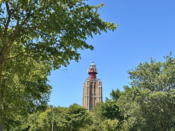 A historic tower with a clock, surrounded by lush green trees.