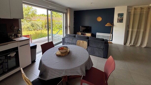 En moderne opholdsstue med spiseområde, køkken og en stor skydedør til udeområdet.