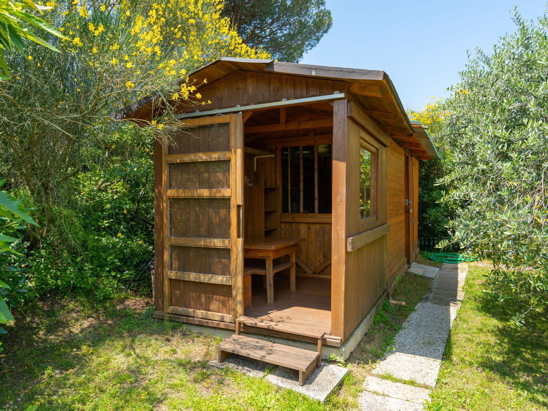 A wooden cabin with a porch, a bench, and a small table.