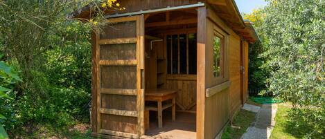 A wooden cabin with a porch, a bench, and a small table.