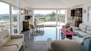 A spacious living room with a large sliding glass door leading to a balcony. The room features a sofa, armchairs, a coffee table, and a television on a cabinet. - Beautiful  villa with A/C, private pool, WIFI, TV, terrace, pets allowed and panoramic view (Montelupo Fiorentino)
