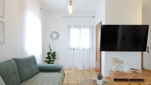 Ein Wohnzimmer mit einer Couch, einem Couchtisch, einem Fernseher und einer Pflanze.