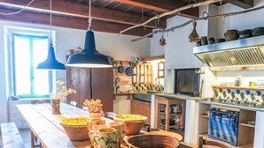 A rustic kitchen with wooden beams, hanging lights, and a variety of cookware and dishes.