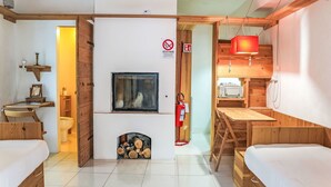 A room with two wooden beds, a wooden table, a fireplace, a TV, and a kitchen area with a red hanging light. - Nice apartment for 2 guests with WIFI, balcony and pets allowed (Strongoli)