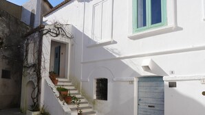 A white building with a blue door, a staircase, and potted plants. - Nice apartment for 2 guests with WIFI, balcony and pets allowed (Strongoli)