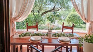A dining table set for two with a view of a garden.