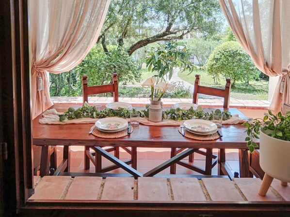 A dining table set for two with a view of a garden.