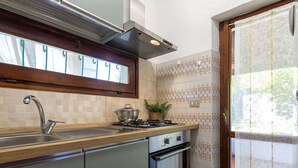 A kitchen with a stainless steel sink, a stove, and an oven.