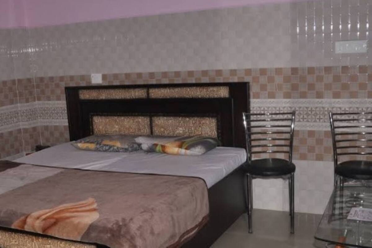 A bedroom with a bed, two chairs, and a small table.