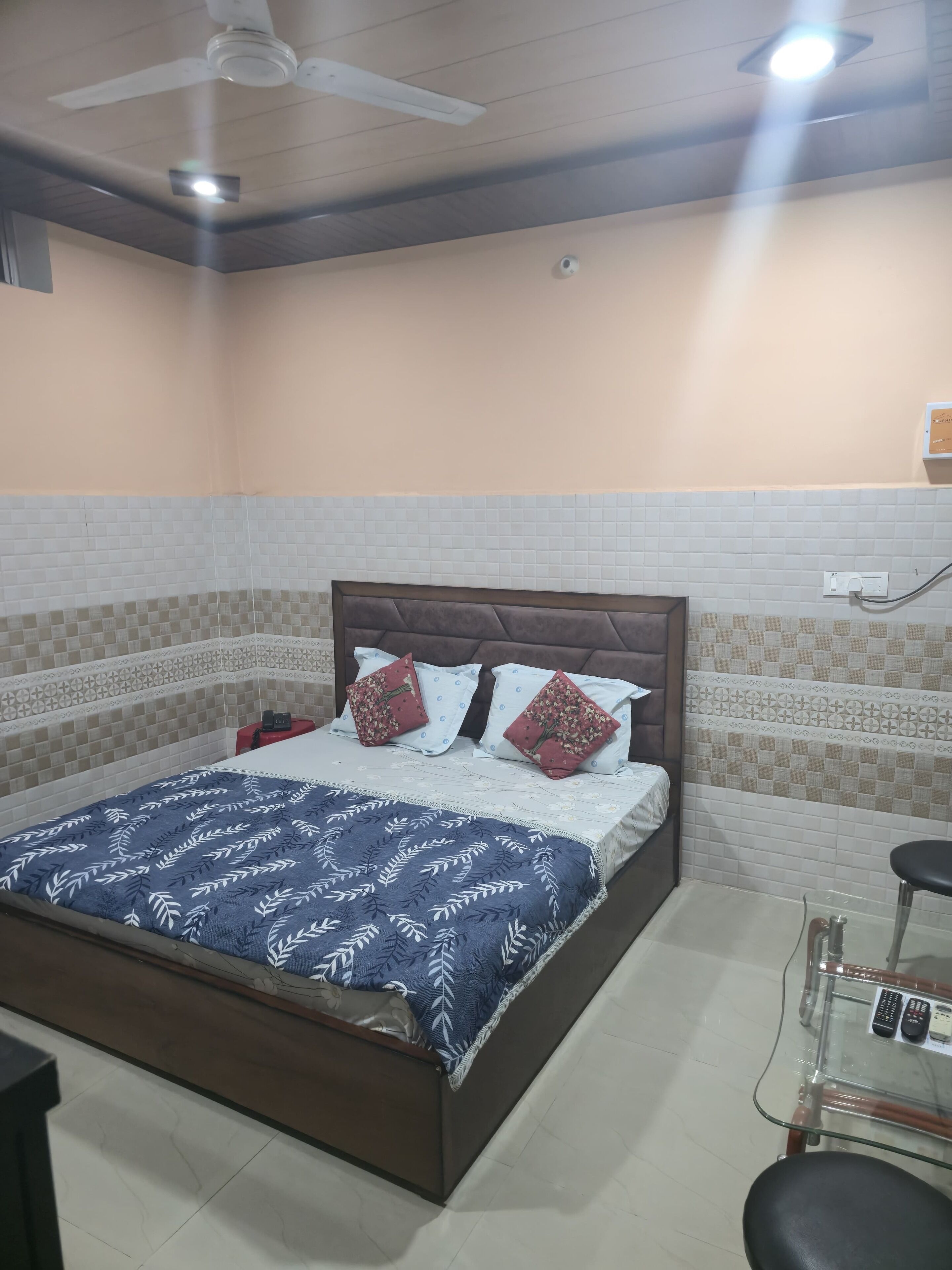 A bedroom with a bed, a ceiling fan, and a nightstand with a lamp.