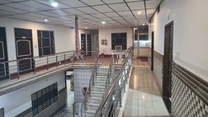 A multi-level interior with a central staircase, railings, and a tiled floor. - Hotel kailash parvat (Amb)