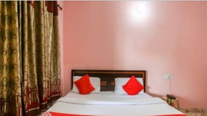 A bed with white bedding and red pillows, a wooden headboard, and a red and white patterned bedspread. - Hotel kailash parvat (Amb)