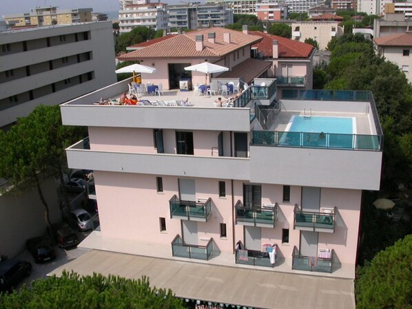Un edificio moderno con piscina en la azotea y zona de estar al aire libre.
