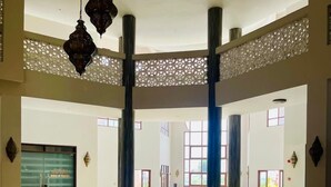 A spacious lobby with a glass coffee table, seating area, and decorative elements like hanging lanterns and a lattice partition. - Luxury Oceanline Apartments-Shaza. (Mombasa)