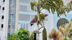 A modern building with a mix of architectural styles, including a prominent arched window and decorative lattice work. - Luxury Oceanline Apartments-Shaza. (Mombasa)