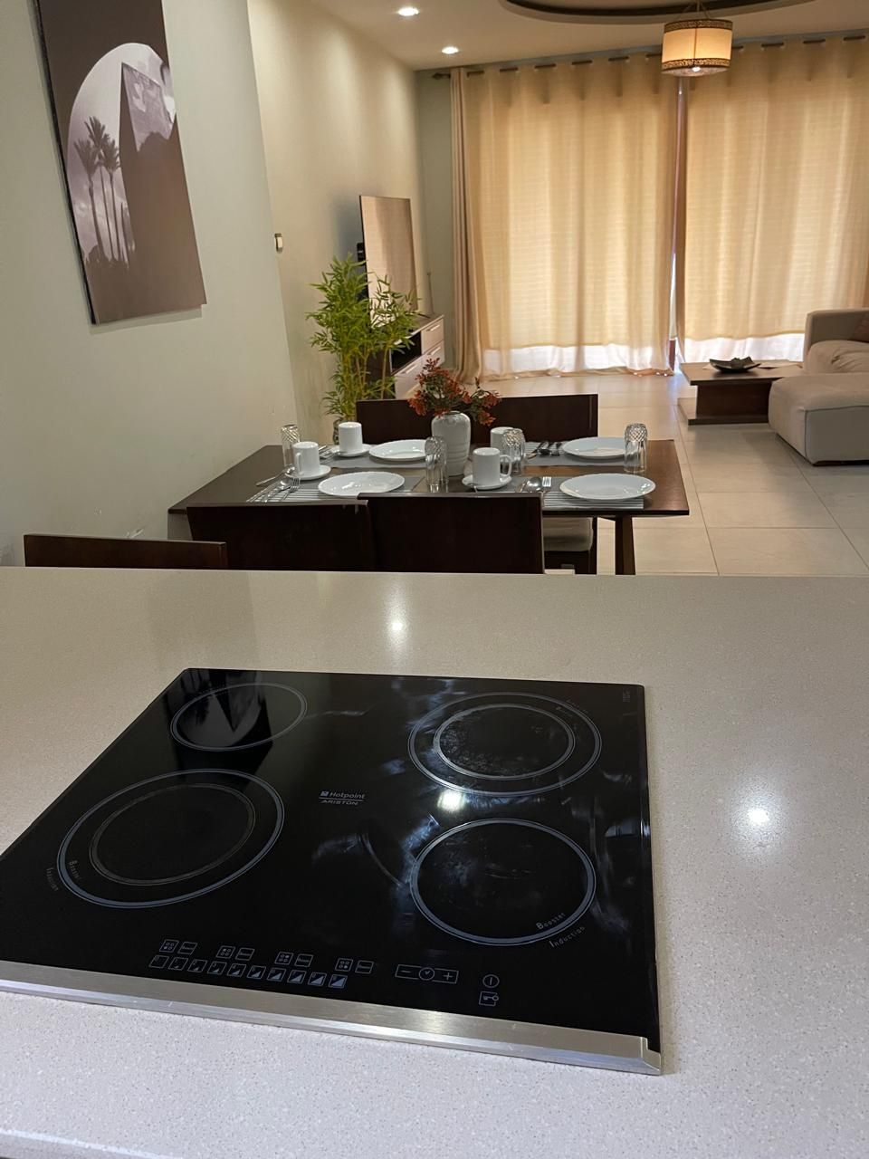 A modern kitchen with a black induction cooktop and a dining area with a table set for four.