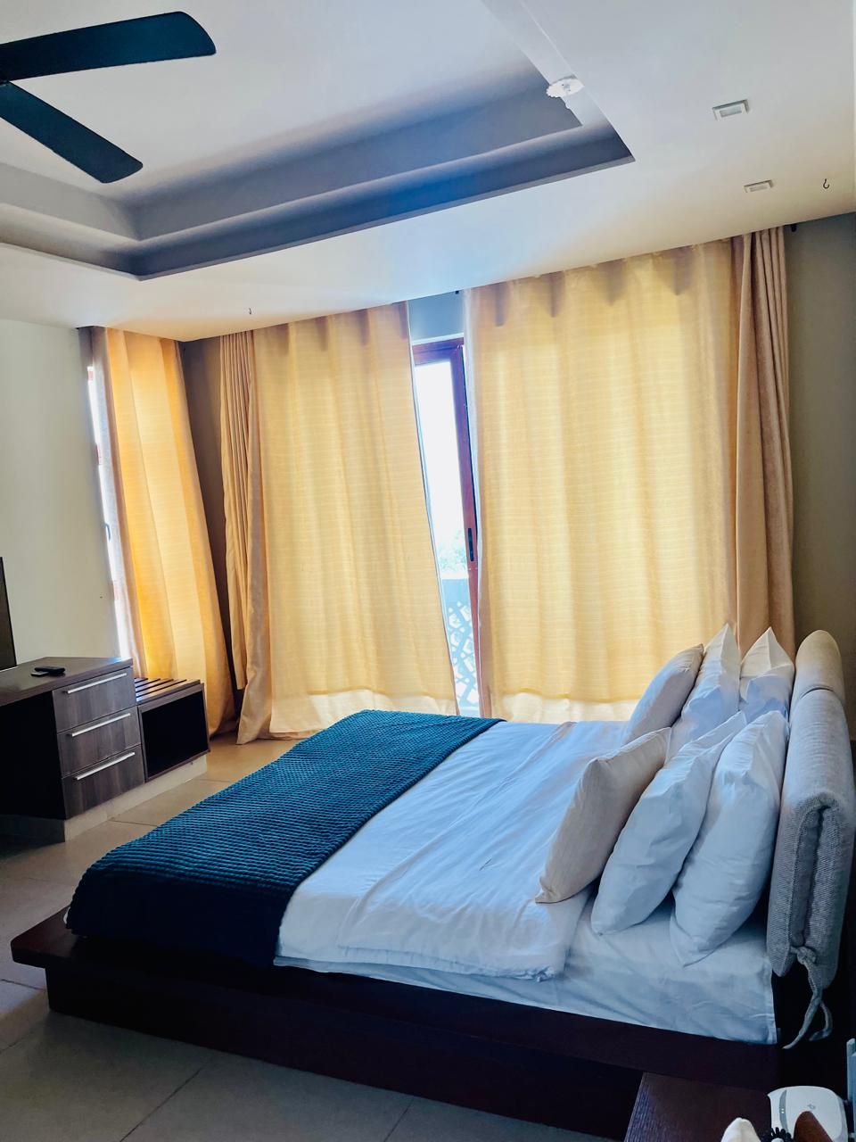A modern bedroom with a large bed, a bedside table, and a window with curtains.