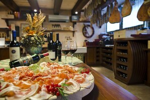 Zona de bar con una selección de vinos, un plato de embutidos y un centro de mesa decorativo.
