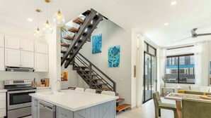 A modern kitchen with a central island, stainless steel appliances, and a staircase with a unique design.