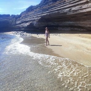 A beach with clear water, a person standing, and rocky cliffs in the background. - Beautiful apartment 10 minutes from the ocean, near the historic center, with a very quiet garage. (Béziers)