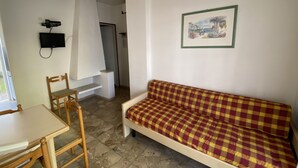 A room with a checkered sofa, a wooden table, a television mounted on the wall, and a framed picture. - Park 17 in Bibione With 2 Bedrooms and 1 Bathrooms (San Michele al Tagliamento)