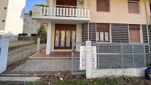 A two-story building with a balcony, a gated entrance, and a sign indicating a rental property. - Park 17 in Bibione With 2 Bedrooms and 1 Bathrooms (San Michele al Tagliamento)