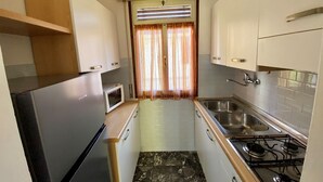 A compact kitchen with a refrigerator, microwave, sink, and stove. - Park 15 in Bibione With 2 Bedrooms and 1 Bathrooms (San Michele al Tagliamento)