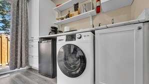 Une cuisine compacte équipée d’un lave-linge, d’un lave-vaisselle et d’un plan de travail sur lequel sont disposés divers ustensiles de cuisine.