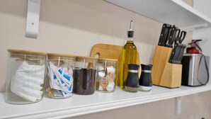 Une étagère de cuisine contenant des bocaux remplis de divers articles, comme des chiffons, du café et des épices.