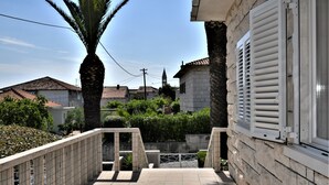 Un balcon doté d’un sol carrelé, d’un palmier et d’un mur en pierre avec des volets.