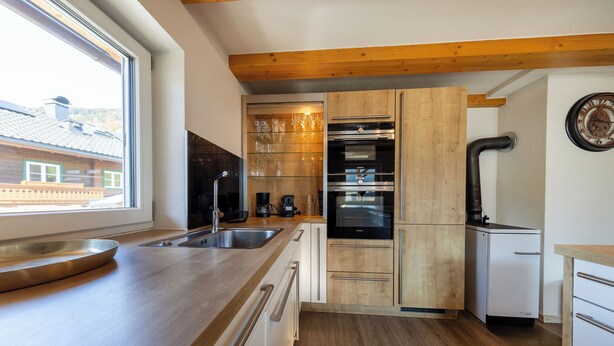 Eine moderne Küche mit Holzschränken, Edelstahlgeräten und einem großen Fenster.