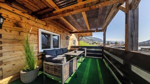 Eine Holzhütte mit Balkon, einer Couch und einem Tisch.