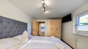 Ein Schlafzimmer mit einem großen Bett, einem Holzschrank und einem an der Wand befestigten Fernseher.