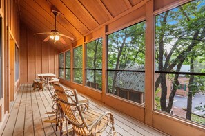 A wooden deck with tables and chairs, large windows, and a ceiling fan. - Family-Friendly Cabin | Step-Free Entry | Accessible Bath | Pet Friendly | Near Branson Strip (Branson)